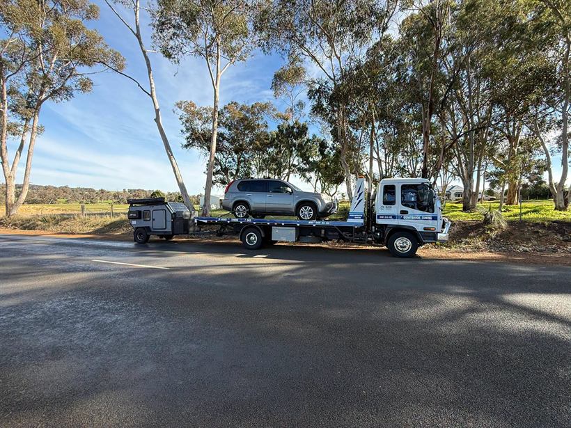 Tilt tray carrying an SUV and towing a camper trailer
