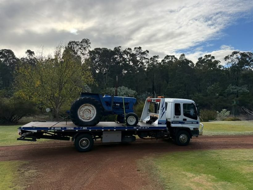 Blue tractor loaded on the tilt tray